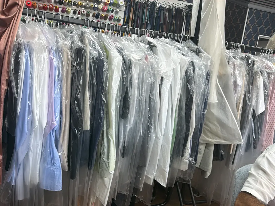 A rail of finished shirts and garments in clear covers, ready for collection