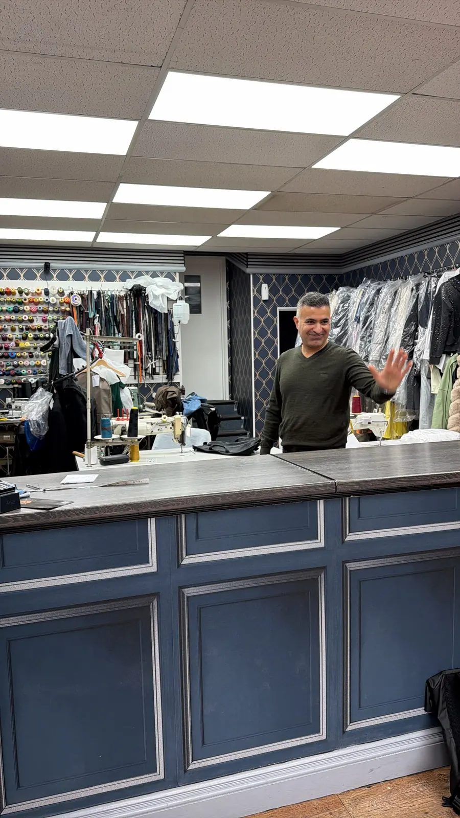 The tailor waving hello from inside the Best Stitch shop